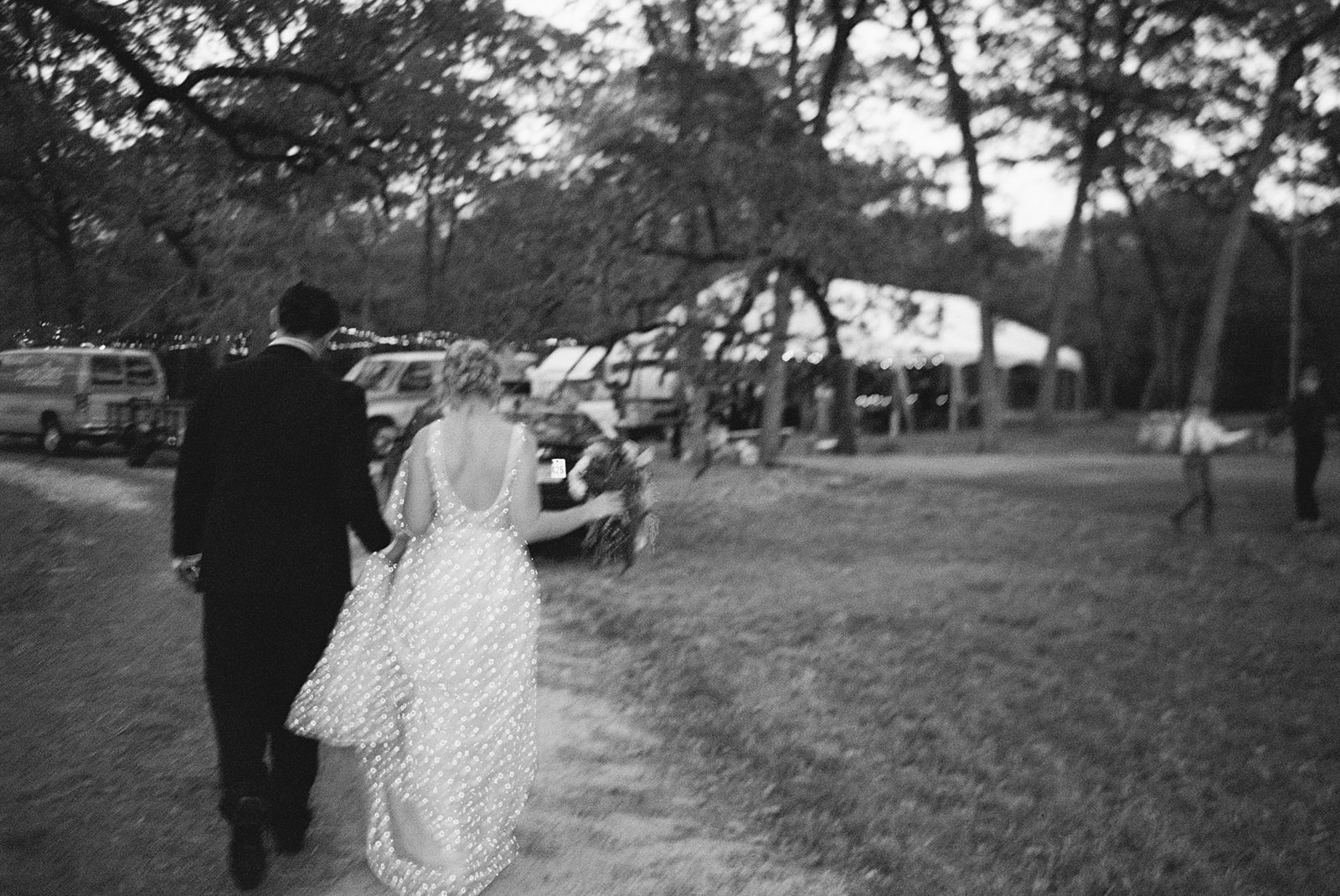 black and white film photo of couple walking to their private estate wedding reception