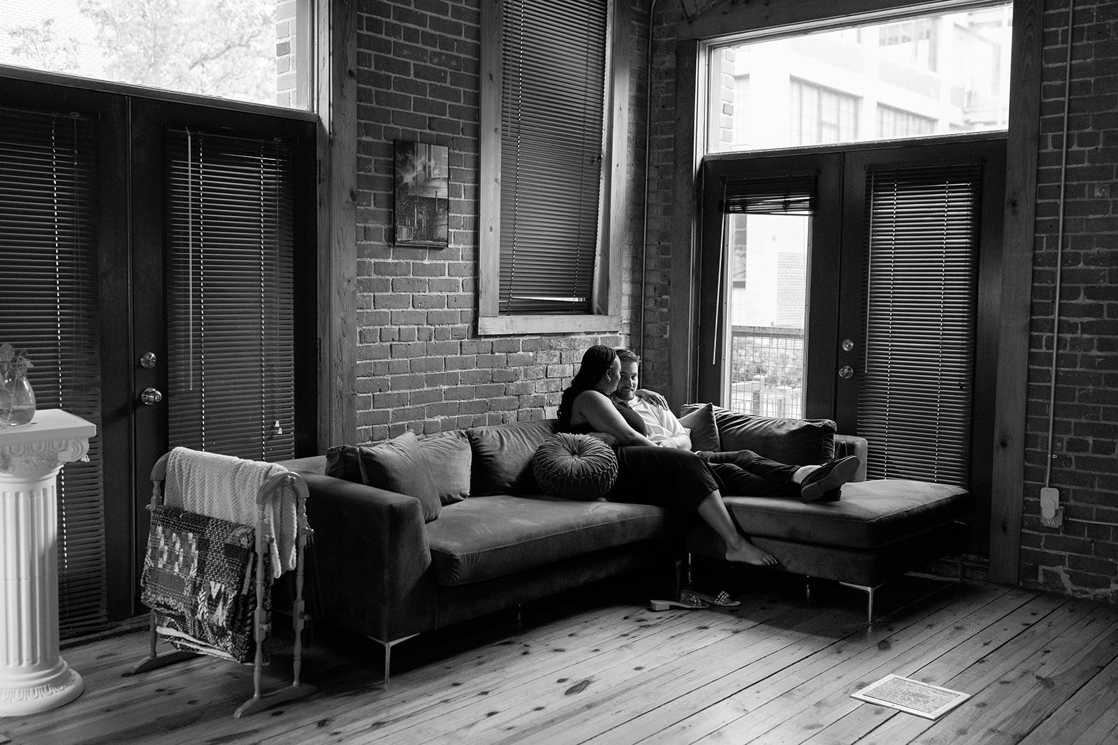 couple sitting on couch in their apartment during engagement session