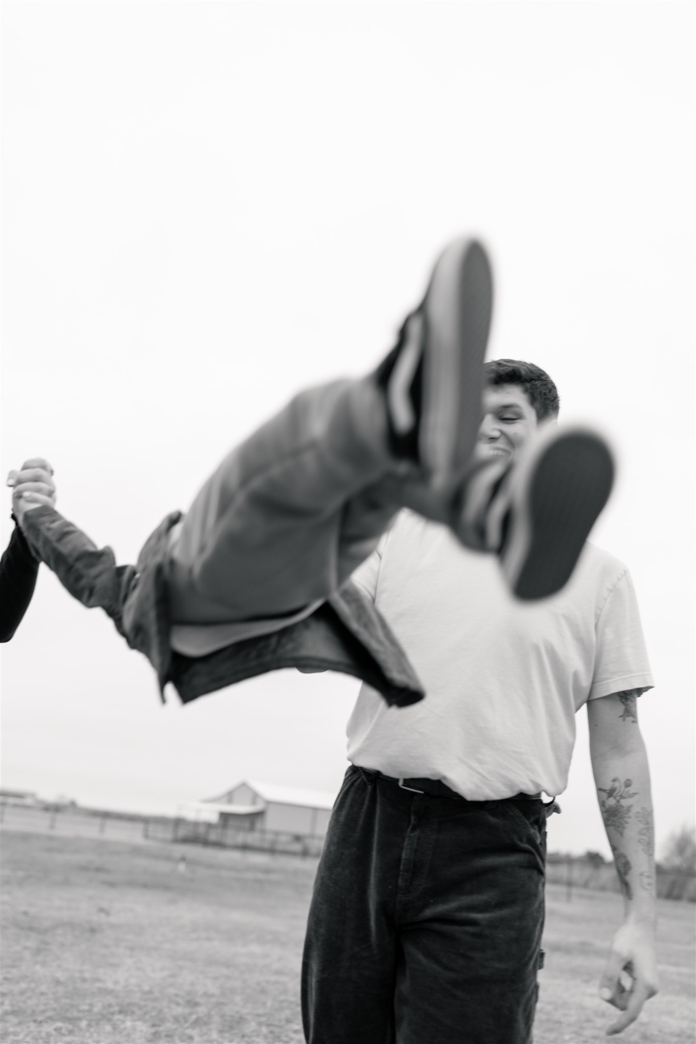 black and white documentary photo of parents swinging their child