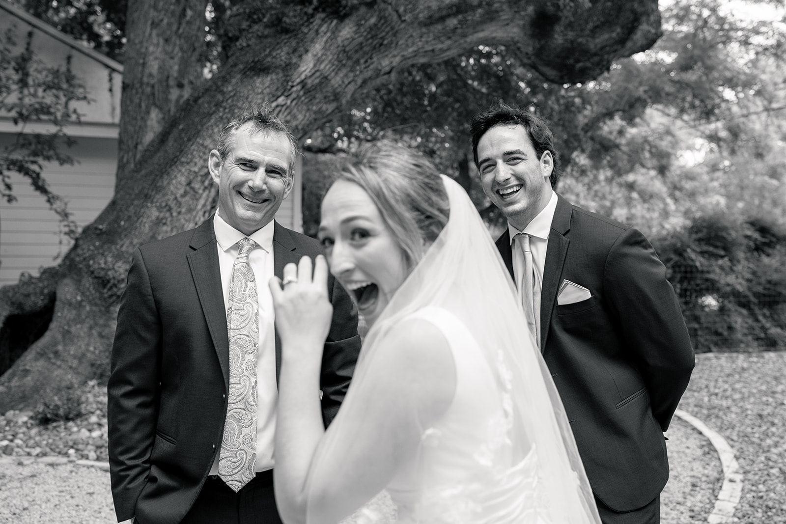 a bride happy crying and looking back at the camera after her first look with her smiling father and brother